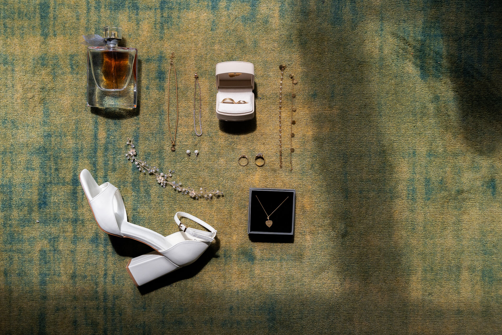 Schuhe, Parfum, Ringbox und Schmuck der Braut auf dem Teppich