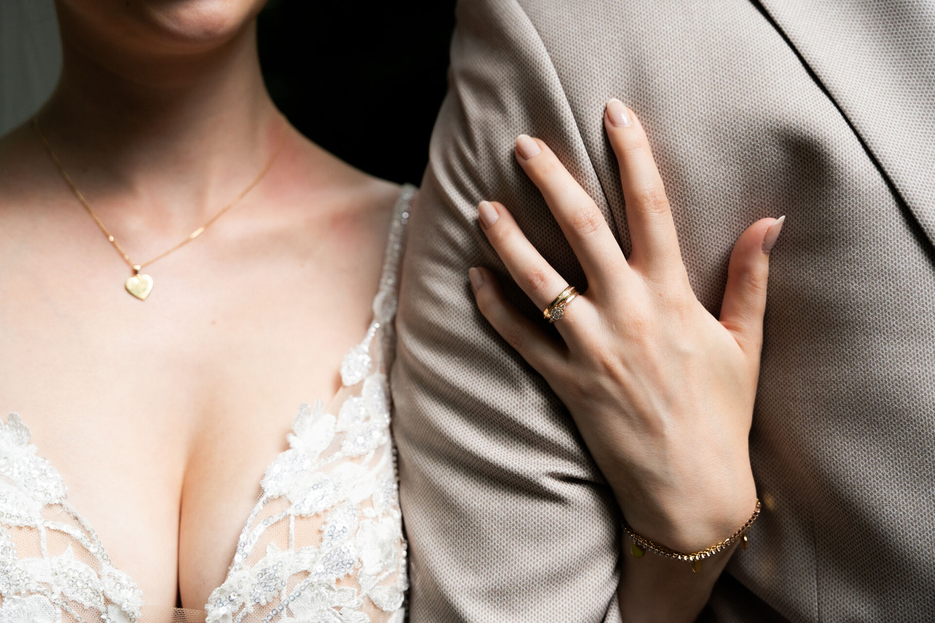 Kette der Braut und ihre Hand am Revers des Bräutigams