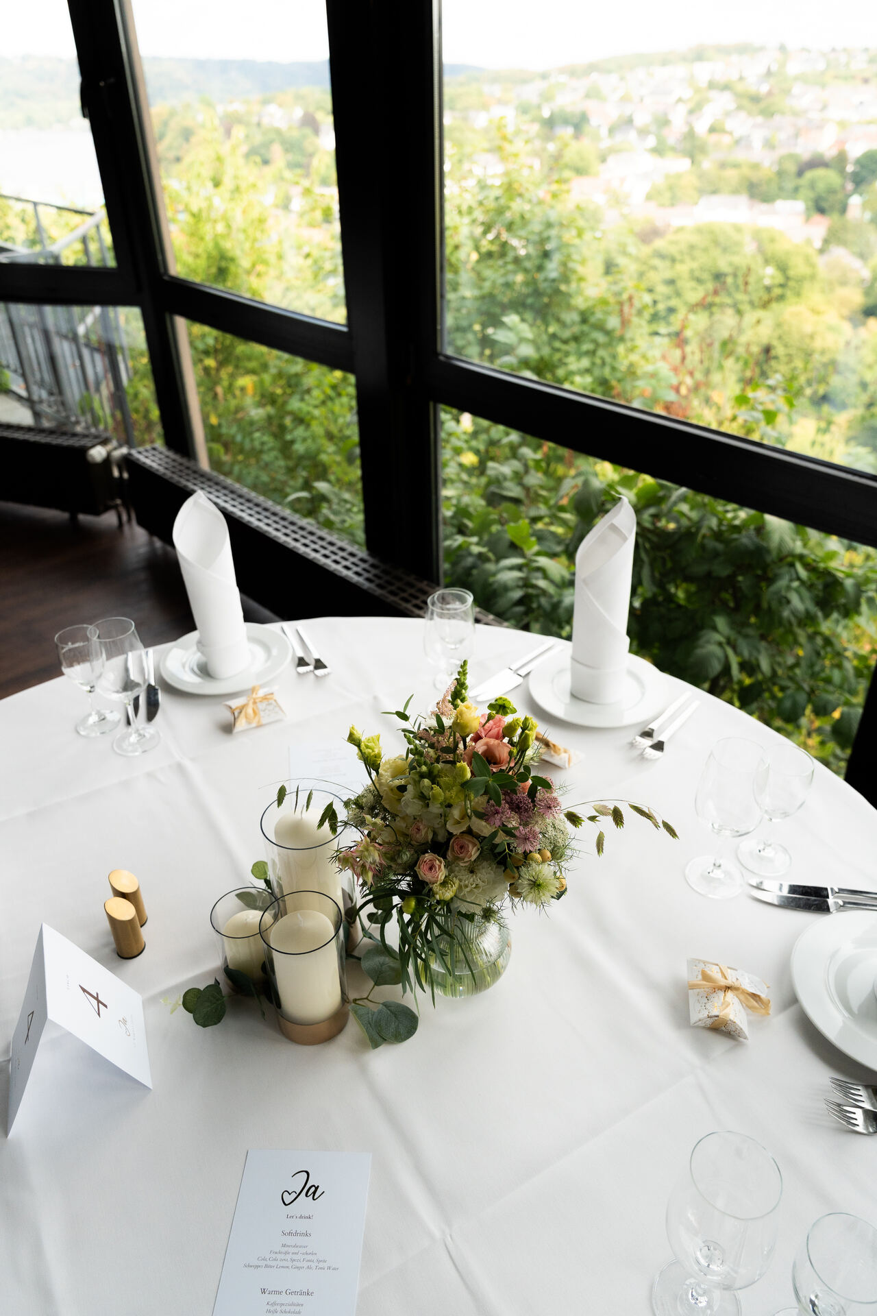 Tischdeko mit Blumen am Fenster, dahinter Essen-Werden