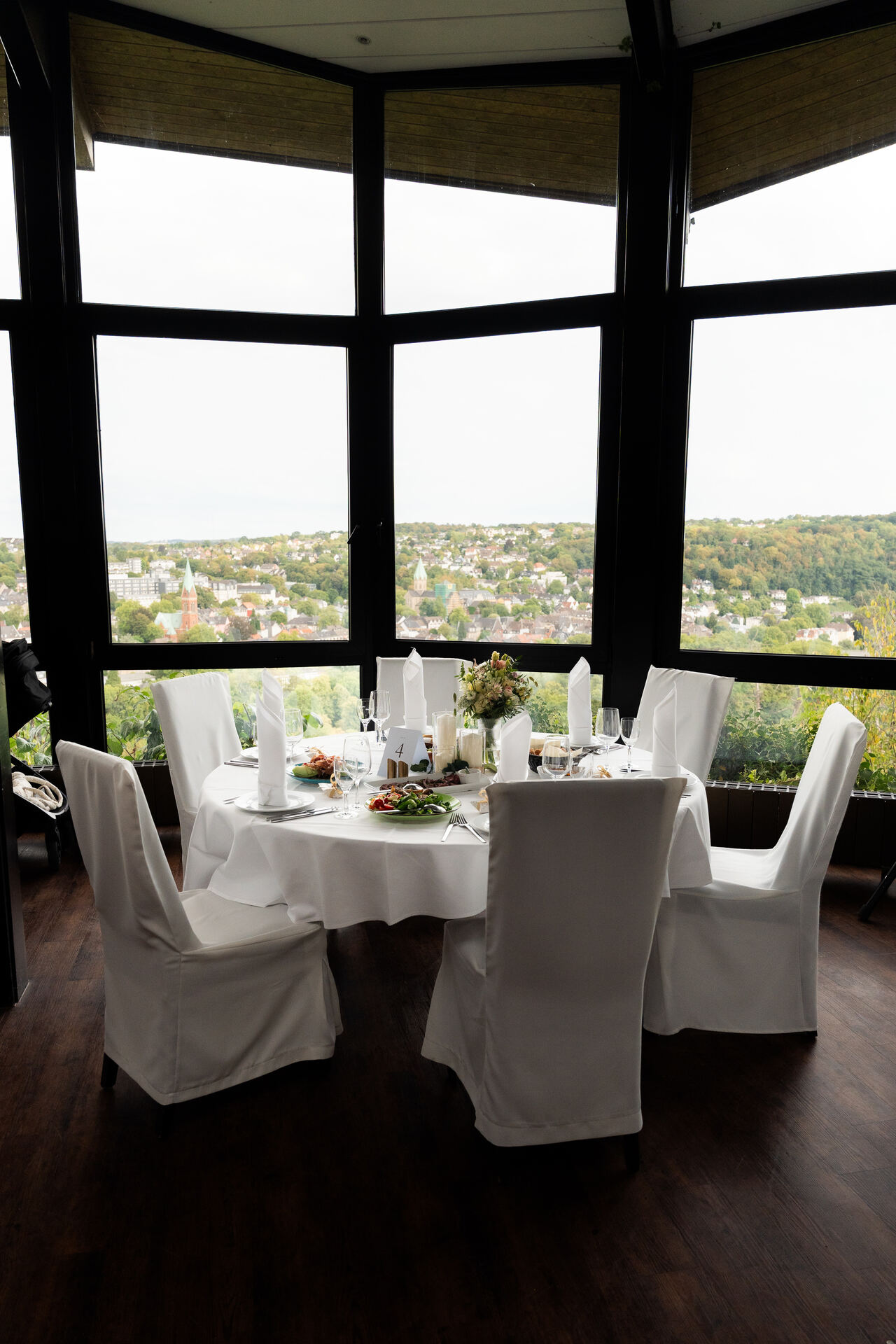 Gedeckter runder Tisch im Saal, dahinter die Fensterfront mit Blick ins Tal